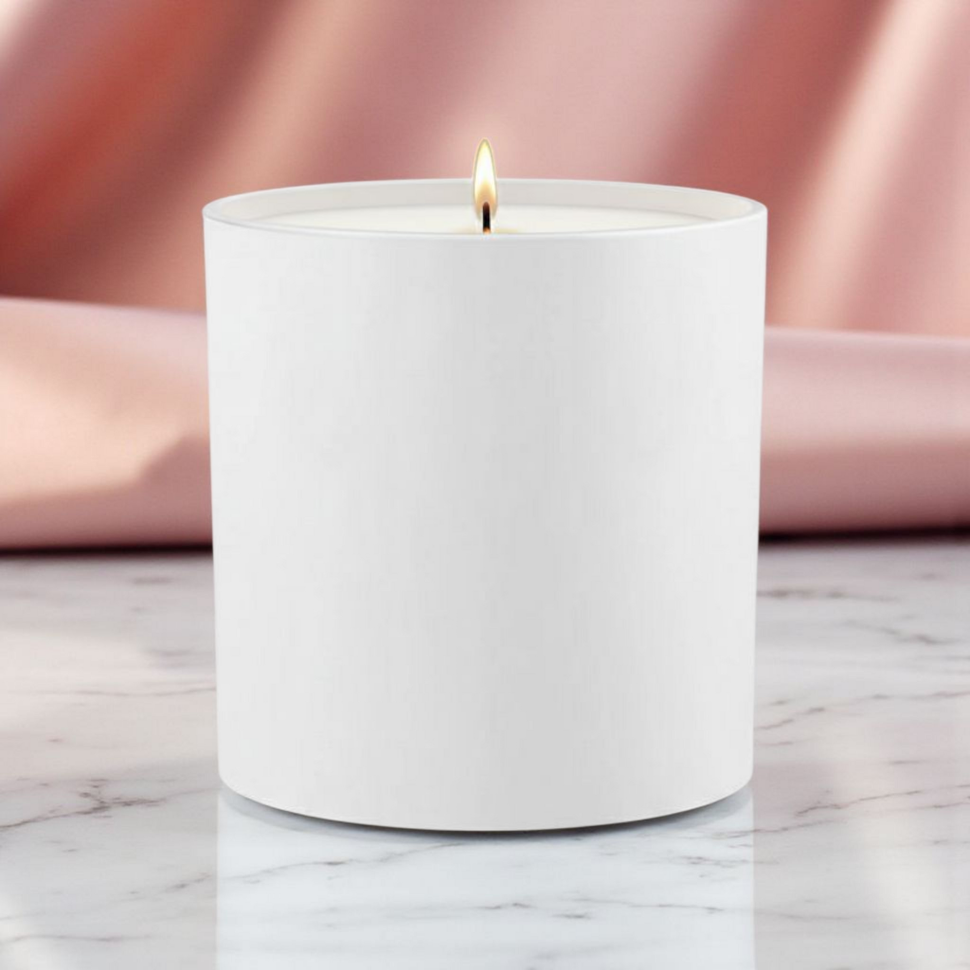 White candle with a lit wick on a marble surface with a pink fabric background