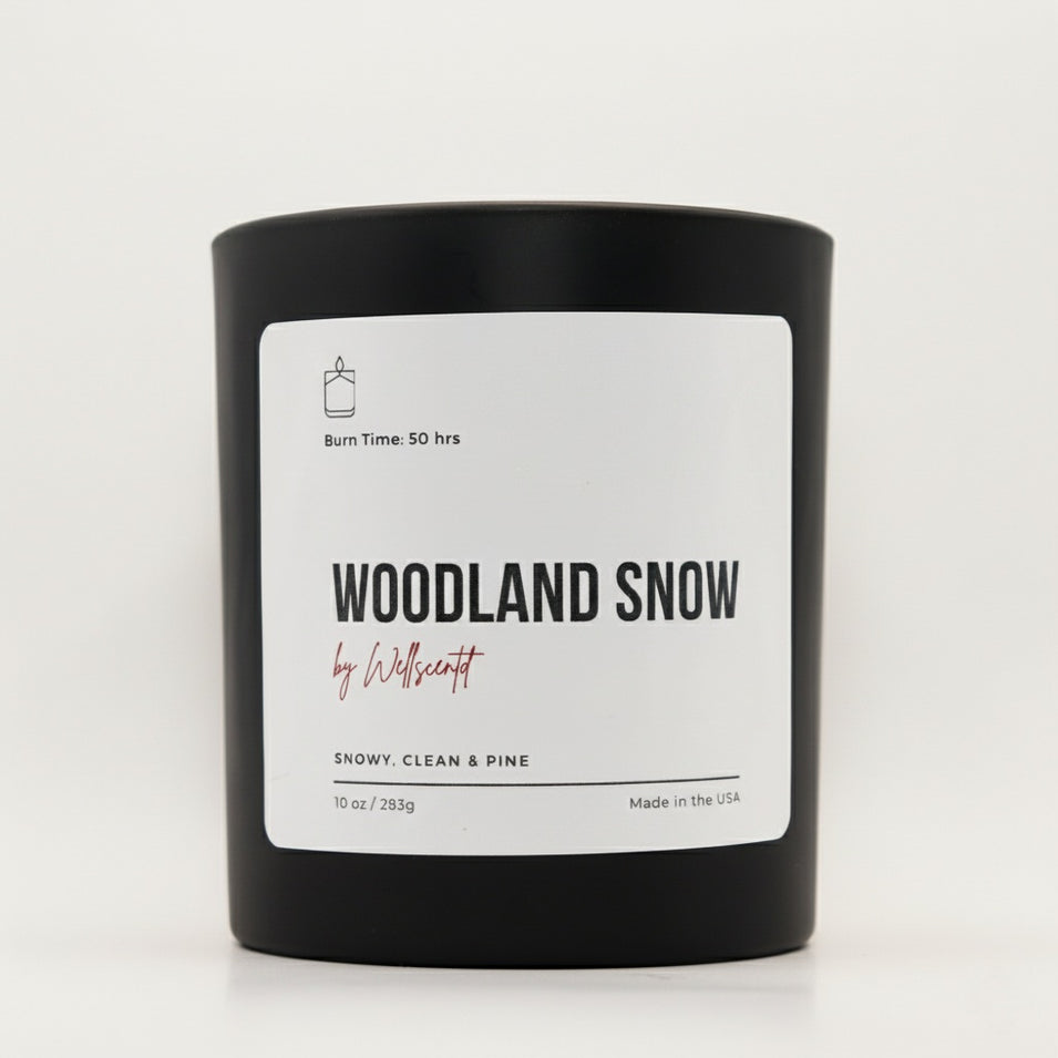 Black candle with 'Woodland Snow' label on a white background