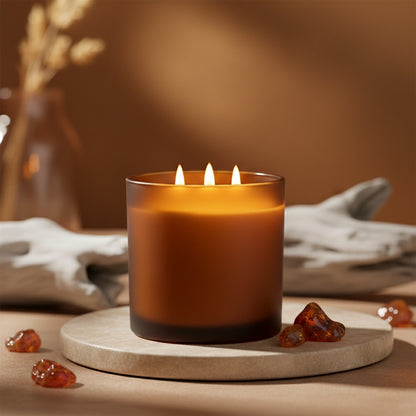 Candle with three flames on a stone surface with amber-colored stones and a blurred background