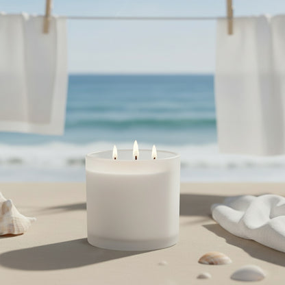 White candle with three flames on a sandy surface with ocean view