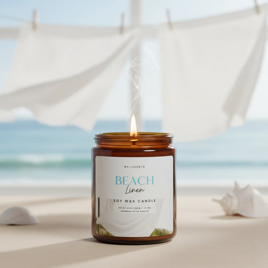 Candle labeled 'Beach Linen' on a sandy beach with ocean view