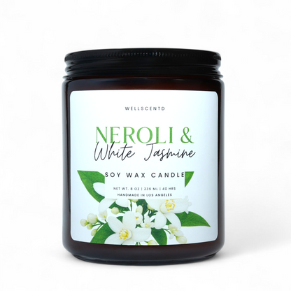 Amber glass Wellscentd Neroli & White Jasmine Candle with green-white label and floral accents on neutral backdrop.
