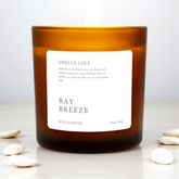 Candle with a label indicating 'Smells Like Bay Breeze' by Wellacento on a white background.