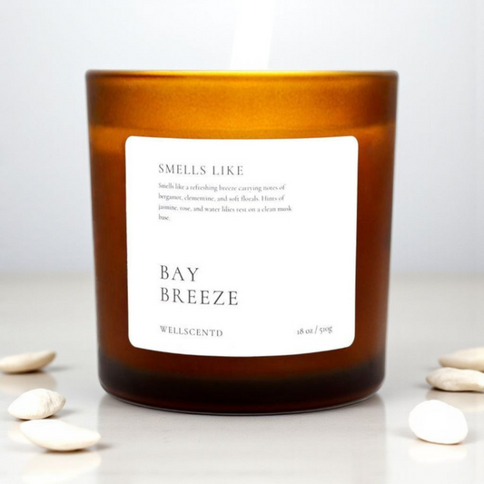 Candle with a label indicating 'Smells Like Bay Breeze' by Wellacento on a white background.