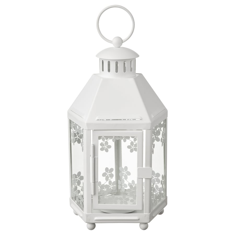 White lantern with floral cutouts on a white background